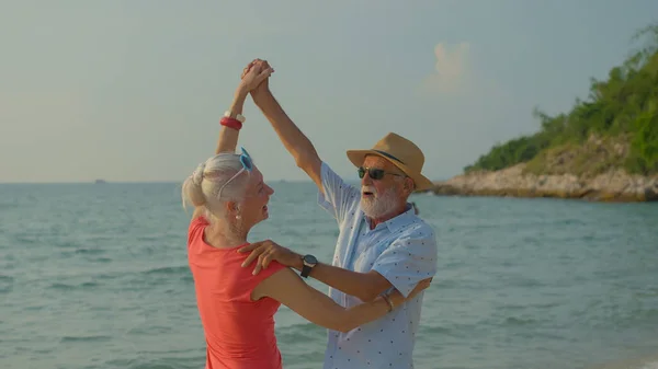 两个老年男女在他们的暑假里在海滩上跳舞 他们笑着享受他们的假期 — 图库照片