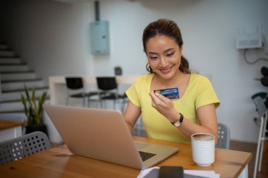 Akıllı telefon ve dizüstü bilgisayarla evde kredi kartıyla alışveriş yapan kadınlar