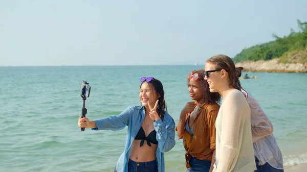 一群年轻女性在暑假时用手机在海滩上自我感觉良好 她们笑着享受假期 — 图库照片