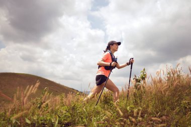 Akşamüstü dağların tepesinde çayırlarda koşan genç kadınlar yürüyüş direğiyle...