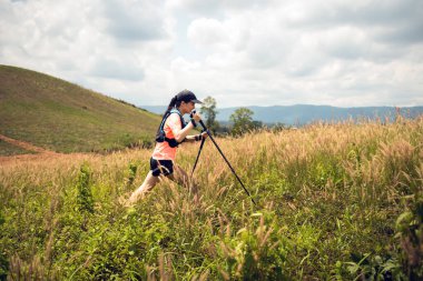 Akşamüstü dağların tepesinde çayırlarda koşan genç kadınlar yürüyüş direğiyle...