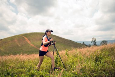Akşamüstü dağların tepesinde çayırlarda koşan genç kadınlar yürüyüş direğiyle...