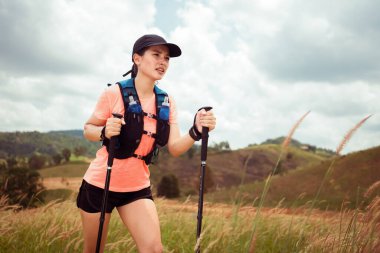 Akşamüstü dağların tepesinde çayırlarda koşan genç kadınlar yürüyüş direğiyle...