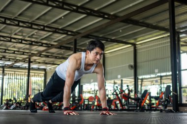 Adam spor salonunda dağa tırmanıyor. Bacaklarını kaldırıp havada hareket eden bir adam. Spor salonu konseptinde sağlık hizmeti.