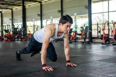 Adam spor salonunda dağa tırmanıyor. Bacaklarını kaldırıp havada hareket eden bir adam. Spor salonu konseptinde sağlık hizmeti.