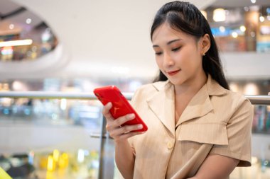 Gündelik giyinen genç bir kadın alışveriş merkezinde kredi kartıyla online alışveriş torbaları taşıyor.