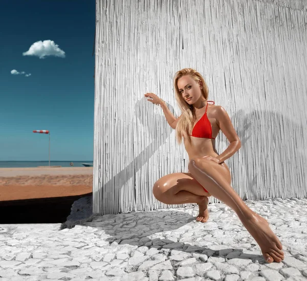 白い色のサントリーニリゾートの海岸にポーズをとって 赤いビキニで完璧な足を持つ美しい女性 広角歪み撮影 — ストック写真