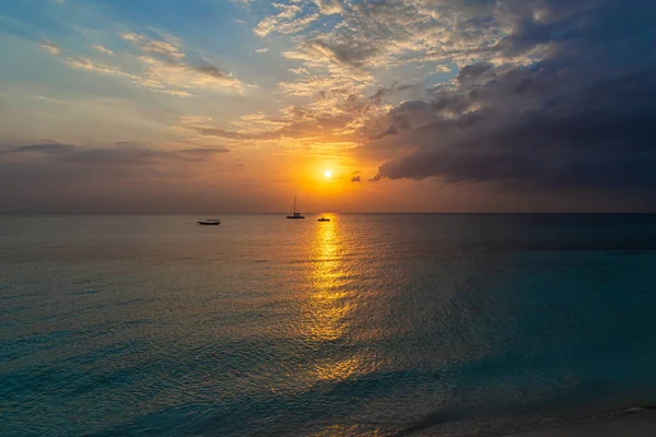 Sunset in the ocean with boats on the horizon line - wide-angle landscape photo of ocean waves.