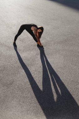 Güneşli yaz günlerinde açık havada egzersiz yapan bronzlaşmış beyaz bir kadın.