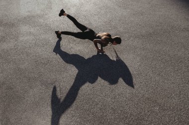 Güneşli yaz gününde, bronzlaşmış beyaz bir kadın dışarıda şınav çekiyor.