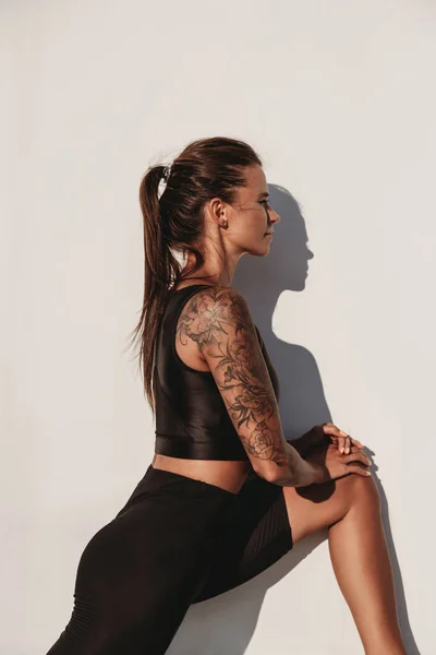 Hermosa Joven Forma Bronceada Mujer Caucásica Tatuada Calentándose Fondo Pared — Foto de Stock