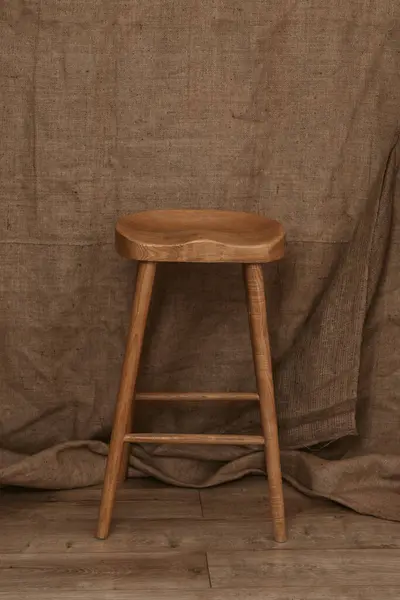 茶色の織物の背景にシングルタールの木製の足のストール ストック画像