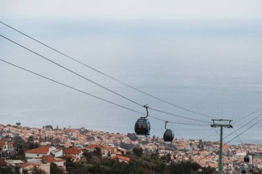Funchal, Madeira, Portekiz - 24.09.2021: Funchal 'da şehir ve okyanusun üzerinde kulübeleri olan kablo araba
