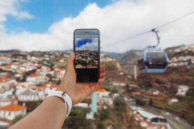 Portekiz 'in Madeira Adası' ndaki Funchal şehrinin üstündeki teleferik kulübesinden fotoğraf çeken kız.