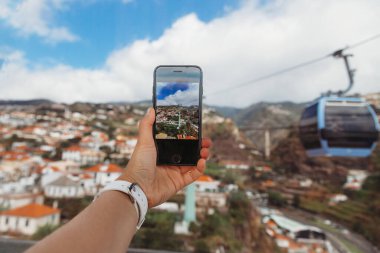 Portekiz 'in Madeira Adası' ndaki Funchal şehrinin üstündeki teleferik kulübesinden fotoğraf çeken kız.