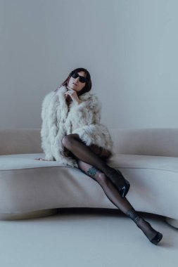 Koltuğunda siyah tayt ve güneş gözlüğü takan seksi beyaz kadın.