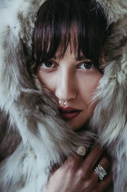 Close up portrait of attractive caucasian woman with fringe and nose piercing with fur around her head clipart