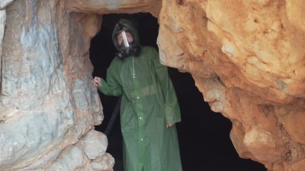 暗い洞窟から出てくるガスマスクを身に着けている女性は 場所を探索し 周りを見回す 象徴的な映像黙示録 化学的 生物学的感染 放射線 — ストック動画