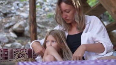 Anne küçük kızının saçlarını okşar ve uzaktan hayallere bakar. Annelik, anne ve kız hareket halinde. Üzgün bir çocuk. Yüksek kaliteli FullHD görüntüler