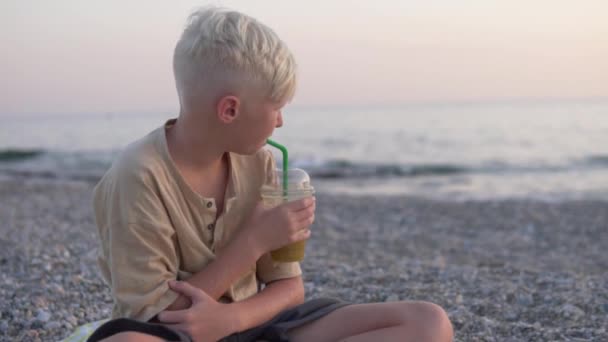 可爱的少年白发男孩在大海的背景上喝新鲜榨的果汁 土耳其 阿拉亚 优质Fullhd影片 — 图库视频影像