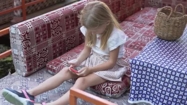 Mała Dziewczynka Bawi Się Telefonem Komórkowym Kawiarni Nad Górską Rzeką — Wideo stockowe