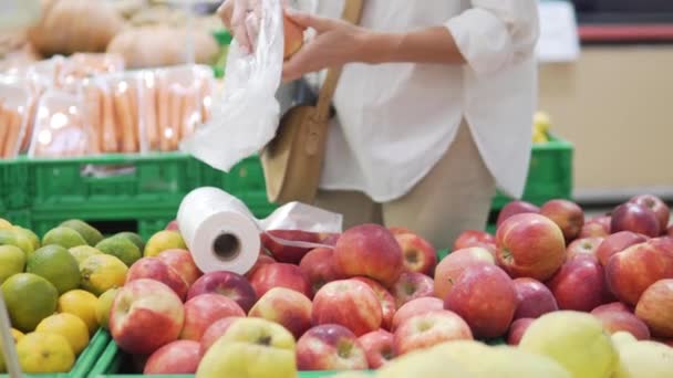 一个女人在杂货店买红苹果 在特写镜头下 女人把多汁的苹果放进商店里的塑料袋里 — 图库视频影像