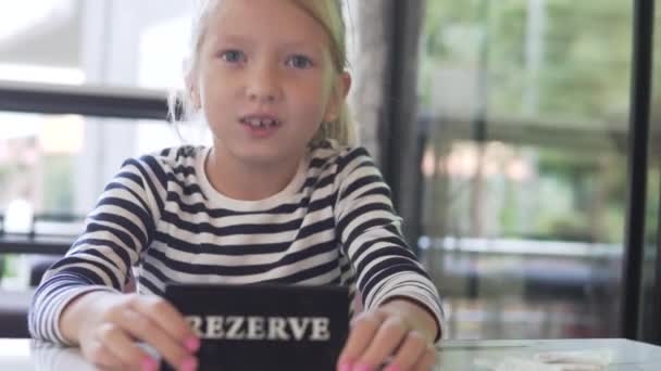 Uma Menina Brinca Com Sinal Reserva Uma Mesa Café — Vídeo de Stock