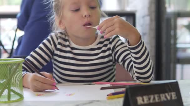 Ένα Κοριτσάκι Μασάει Τσίχλα Και Ζωγραφίζει Μολύβια — Αρχείο Βίντεο