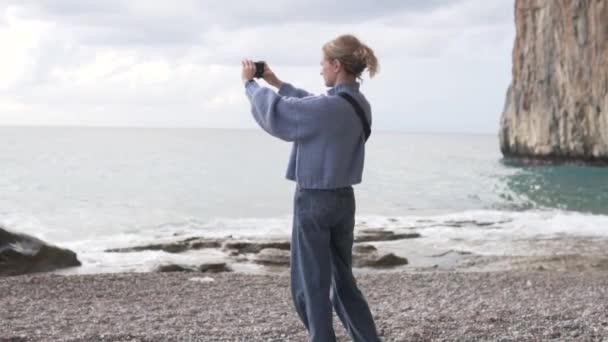 一位女游客在悬崖边的一个美丽的地方给大海拍照 — 图库视频影像