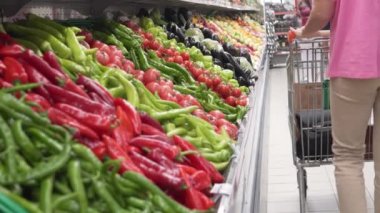 Bir kadın süpermarketten taze sebze alır. Alıcı bir torbada domates topluyor..