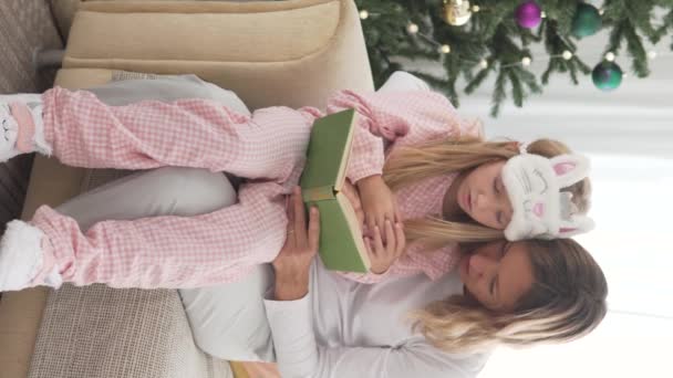 Femeie Citește Carte Fiicei Sale Pomul Crăciun Acasă Video Vertical — Videoclip de stoc
