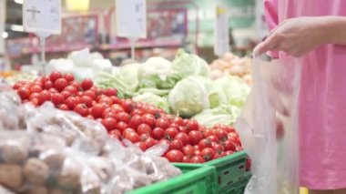 Alıcı marketteki bir poşette küçük domatesleri alıyor..