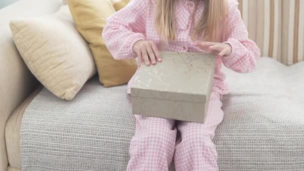 Ein Kleines Mädchen Öffnet Morgens Eine Schachtel Mit Einem Geschenk — Stockvideo