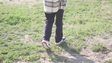 Sonbahar mevsiminde bir patikada yürüyen bir çocuk. Arkadan bak. Çocuk çimlerden kuma dönüyor..