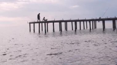 Balıkçılar deniz kıyısındaki iskelede balık tutuyor. Türkiye, Alanya
