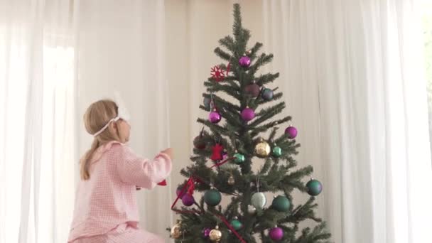 Een Lief Klein Meisje Versiert Een Kerstboom Thuis — Stockvideo