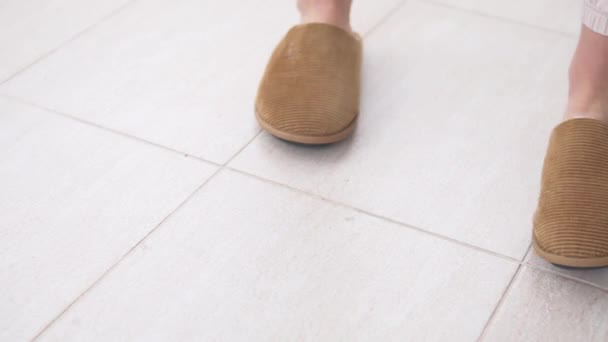 特写时 女人在铺了瓷砖的地板上脱下暖和的拖鞋 然后离开了 — 图库视频影像