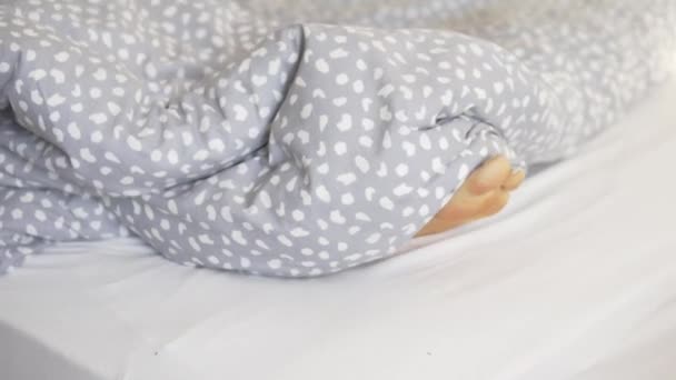 早上睡觉时 女人的脚从温暖的毛毯下向外张望 — 图库视频影像
