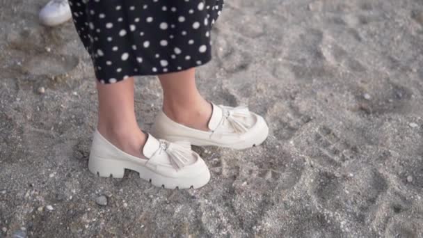 Zbliżenie Kobiece Stopy Białych Butach Platformowych Stojących Piasku Sukienka Kropki — Wideo stockowe