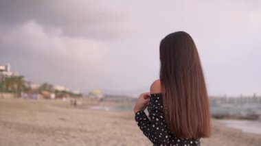 Asya görünümlü güzel bir kız kameraya dönüp büyüleyici bir şekilde gülüyor. Yavaş çekim, günbatımı.