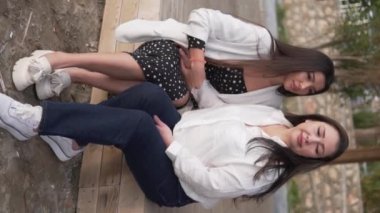 Güzel anne ve gözlük sokakta, kız başını sevgili annesinin omzuna koyar. Dikey video, yavaş çekim, günbatımı ışığı.