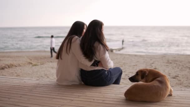 一个漂亮的成年女儿抱着她的母亲 望着大海 在女人旁边坐着一只红狗 在海上度过一个家庭之夜的概念 土耳其 Alanya — 图库视频影像