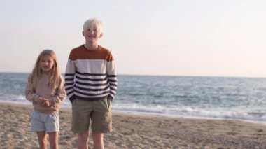 Tatlı çocuklar, erkek ve kız kardeşler, denizin arka planında birbirlerine sarılırlar..