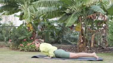 A woman does active yoga in the park in the summer. Turkey, Alanya.
