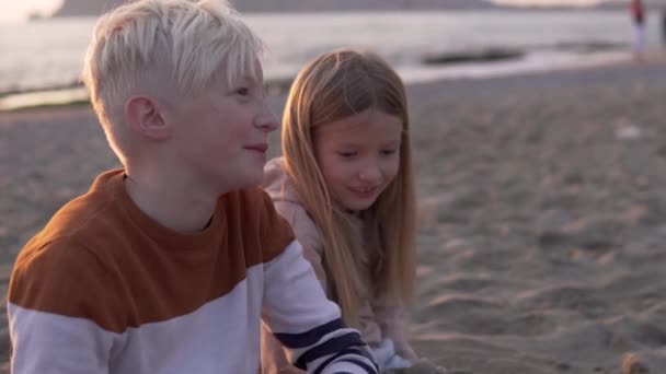 Beautiful Children Brother Sister Sit Beach Blond Boy Speaks His — Stock video