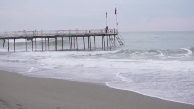 fisherman catches fish on a pier going out to sea in a storm, Turkey, Alanya, December 2023