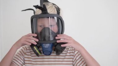 Close-up, a blond boy in a gas mask.