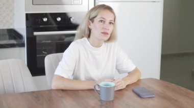 An agitated Woman sits at a table in the morning.