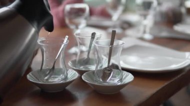 A man pours Turkish tea into cups in a restaurant.