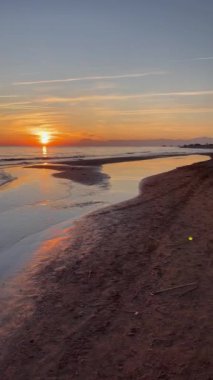 Vertical video, sunset on a deserted beach by the sea.